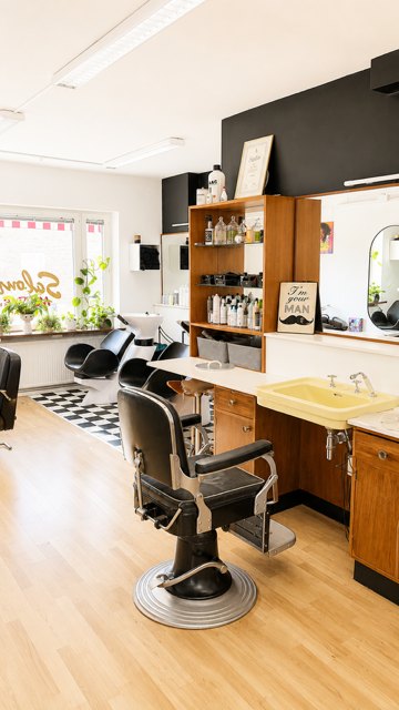 Den gamla barberarstolen vid det svartvita schackrutiga golvet