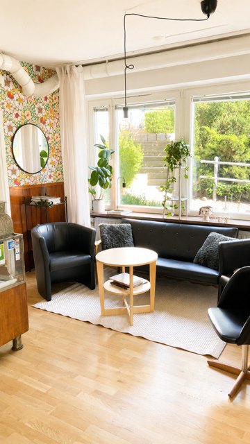 Väntrummet med soffa, fåtöljer och fönster mot grönskan